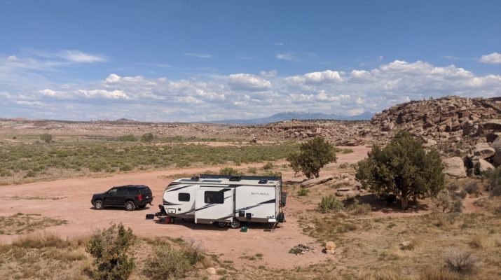 RV sitting on area with piles of rocks and mountains in background