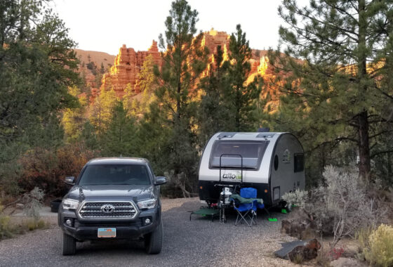 Truck and teardrop camper parked at campsite in canyons