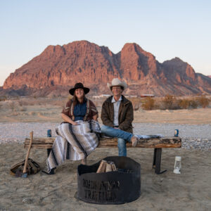 A man and woman sitting on a rustic bench at their RV campground in Texas