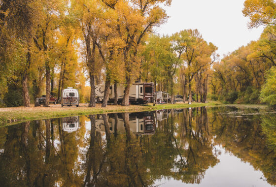 an RV park near the water surrounded by golden fall foliage