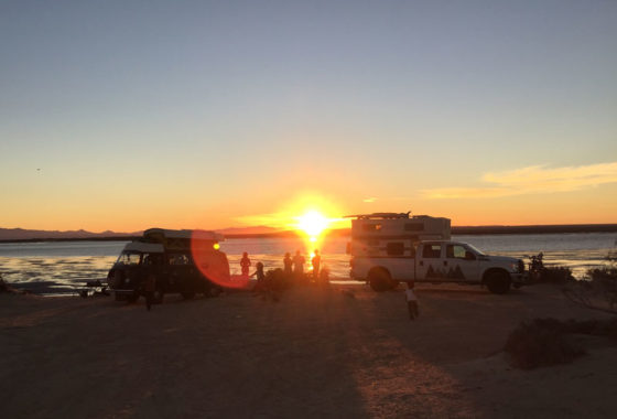 a vw bus and a truck camper parked on a beach in baja